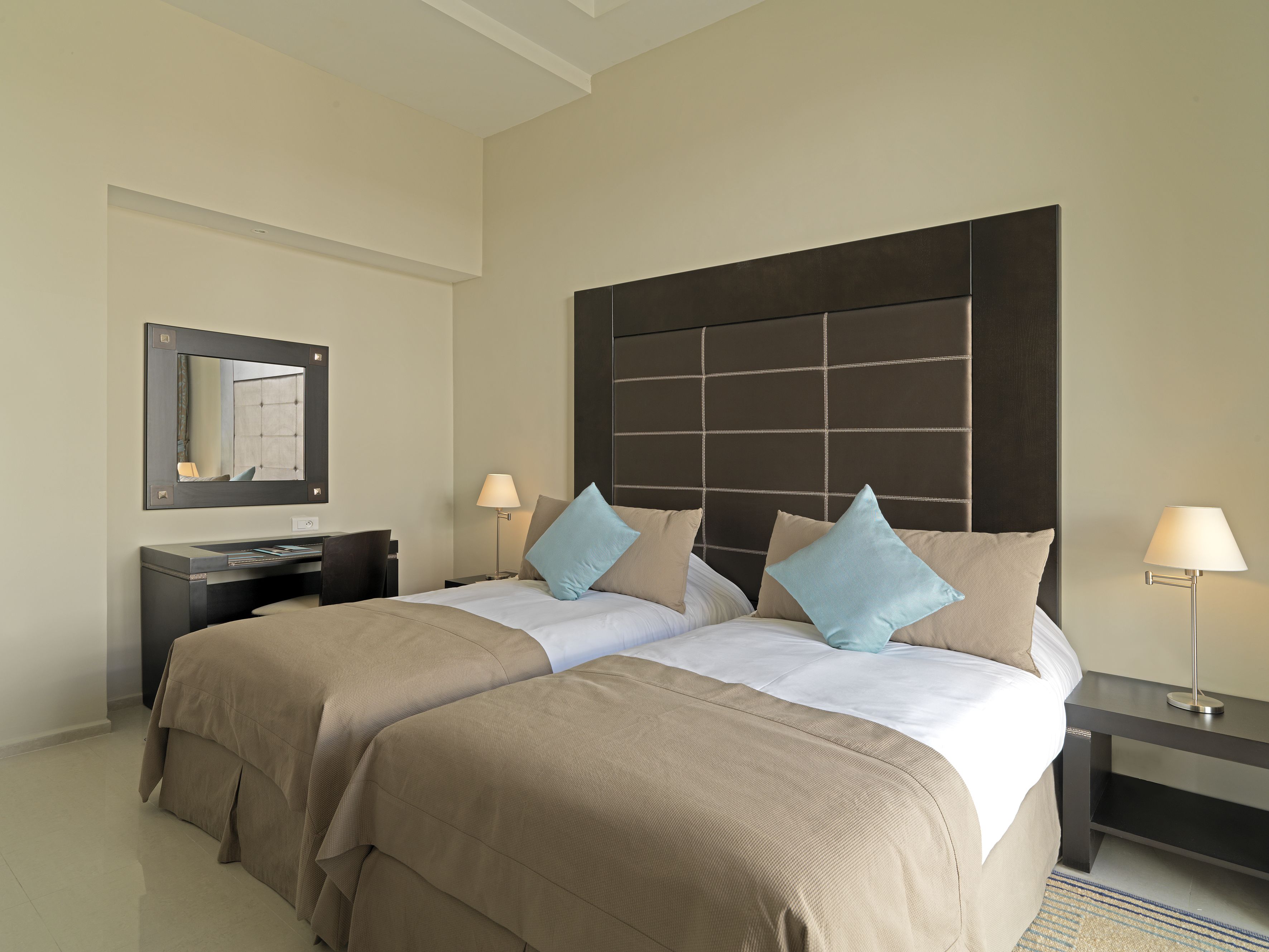 A hotel room with a large bed, two bedside tables, a desk, and a mirror.