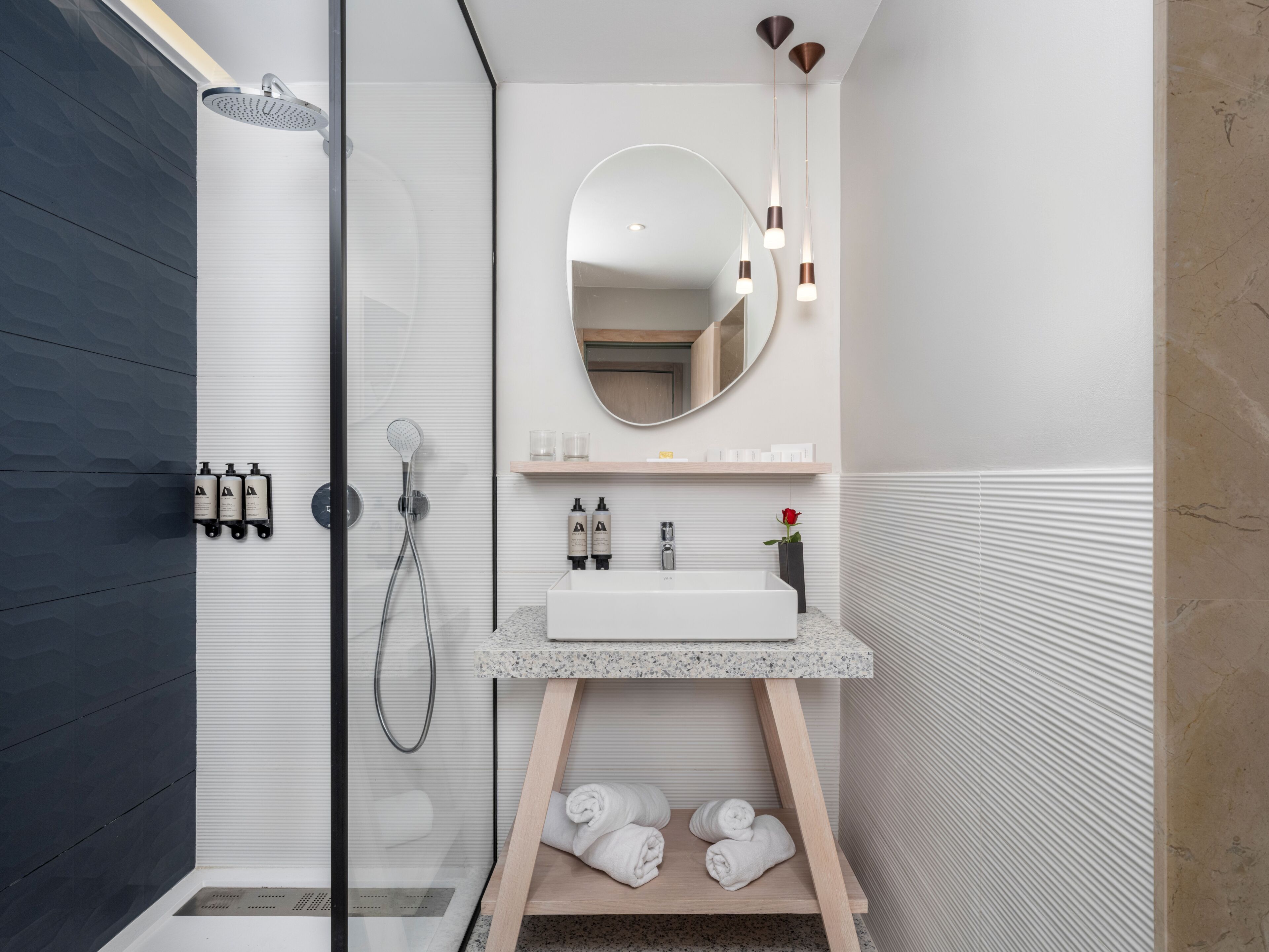 Un bagno moderno dotato di doccia, lavabo, specchio e portasciugamani.