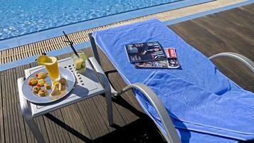 Una piscina al aire libre, sombrillas, tumbonas