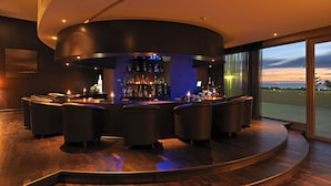 A modern bar area with a curved layout, multiple seating options, and a view of the outdoors. - Atlas Essaouira Riad Resort (Essaouira)