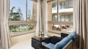 A modern hotel room with large windows, a balcony, and a seating area with a table set for two. - Atlas Essaouira Riad Resort (Essaouira)