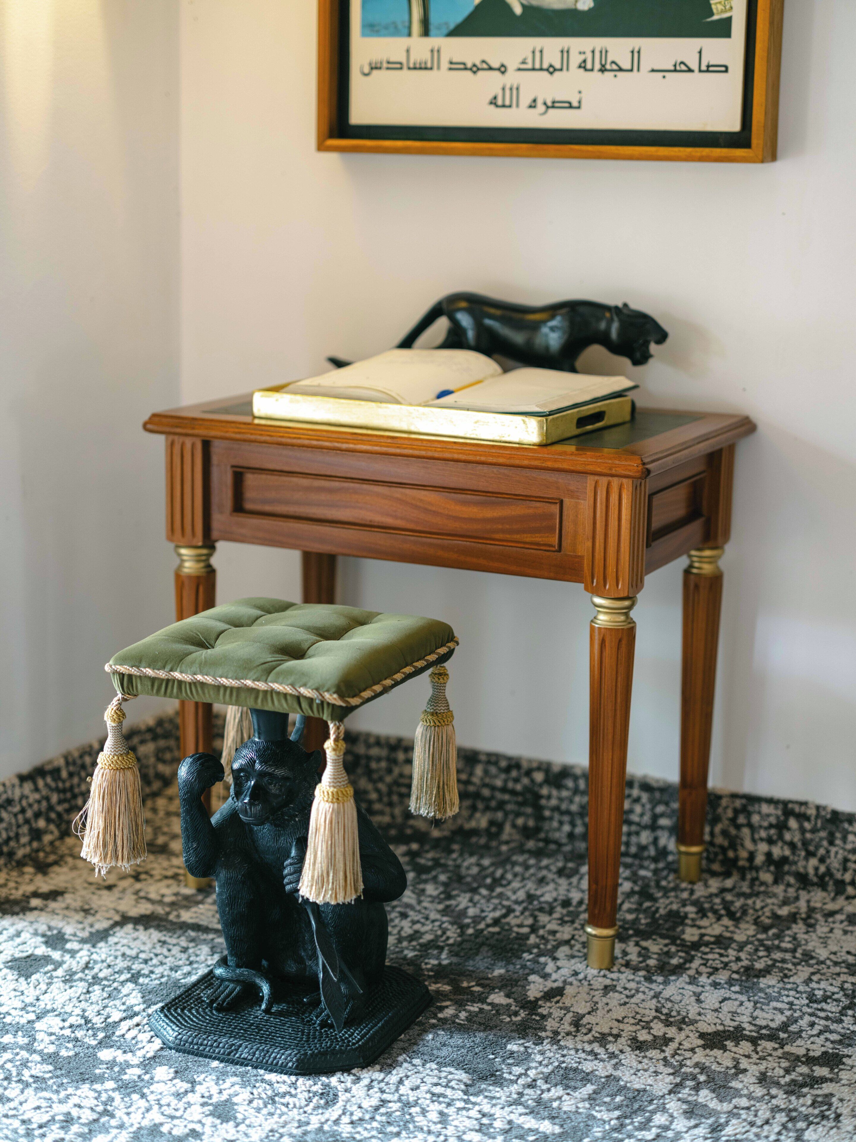 Una pequeña mesa de madera con un libro y una figurita encima.