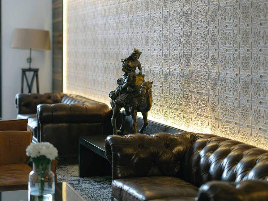 Een moderne woonkamer met een leren bank, een decoratief paardenbeeld en een muur met ingewikkelde kruisdecoraties.