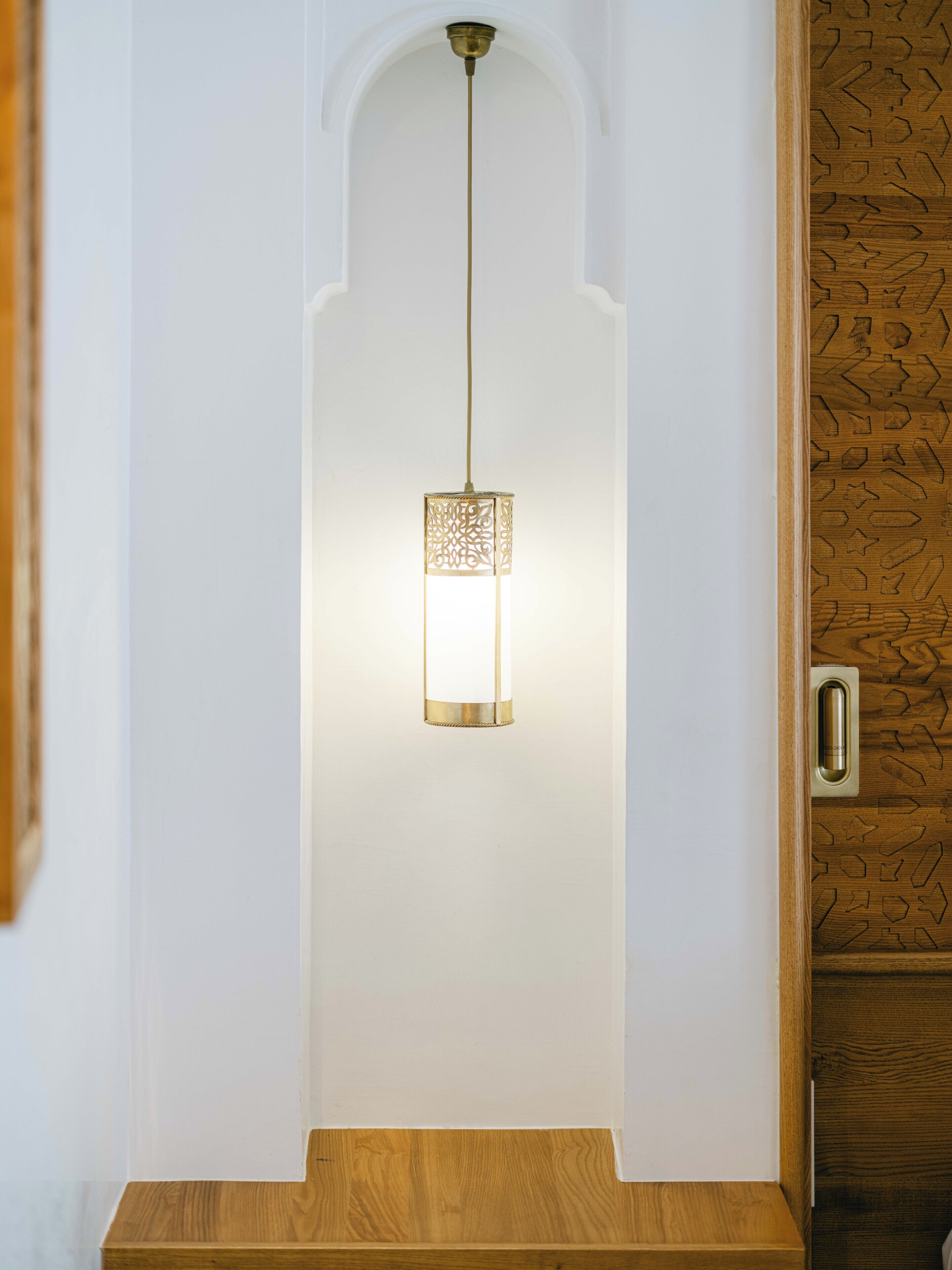 Un interno moderno con una lampada a sospensione e una porta in legno decorata con un motivo geometrico.