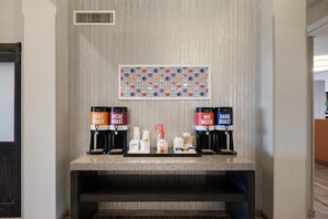 A coffee station with decaf and hot water options, a bottle of Coca-Cola, and a framed picture on the wall. - Hampton Inn North Myrtle Beach-Harbourgate (North Myrtle Beach)
