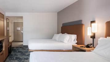 Ett hotellrum med två sängar, ett skrivbord, en telefon och en lampa.