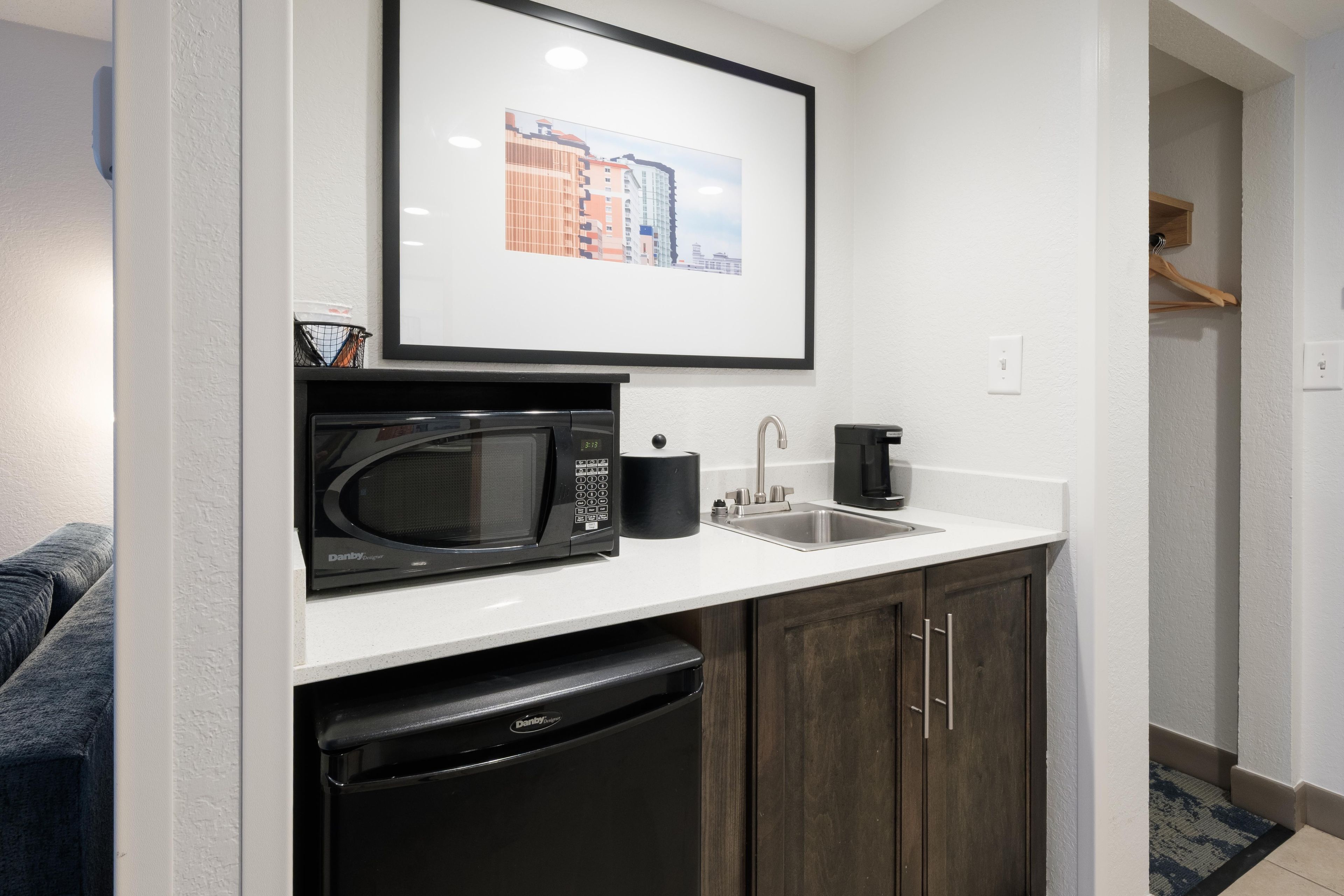 Una kitchenette compacta con microondas, cafetera y lavavajillas.