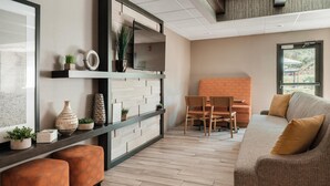Una sala de estar moderna con sofá, otomanas, televisor y un comedor con sillas y una mesa.