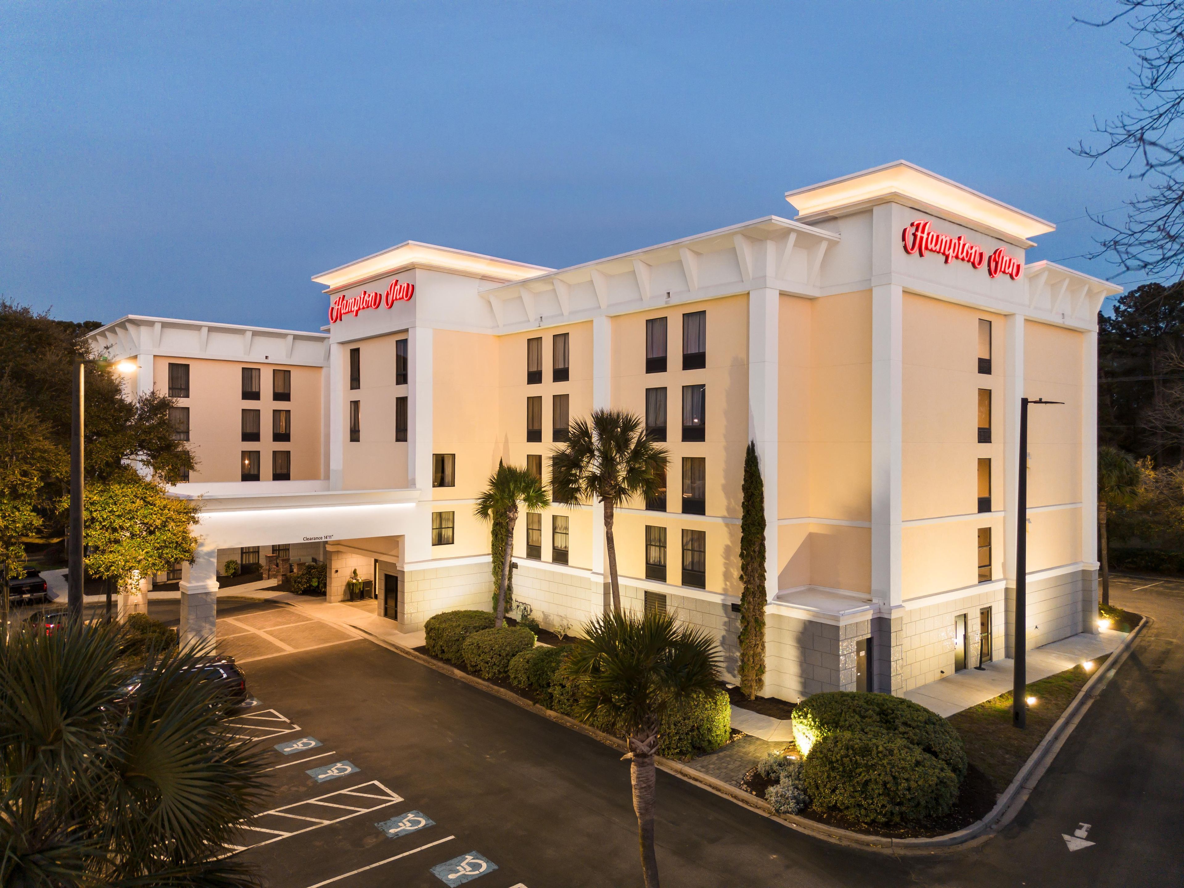 A hotel with a clear entrance, a parking lot with handicapped spaces, and a well-lit facade.