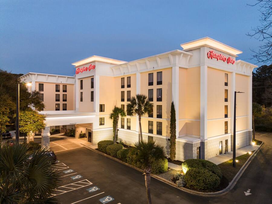 Un hotel con entrada accesible, aparcamiento con plazas para discapacitados y fachada bien iluminada.