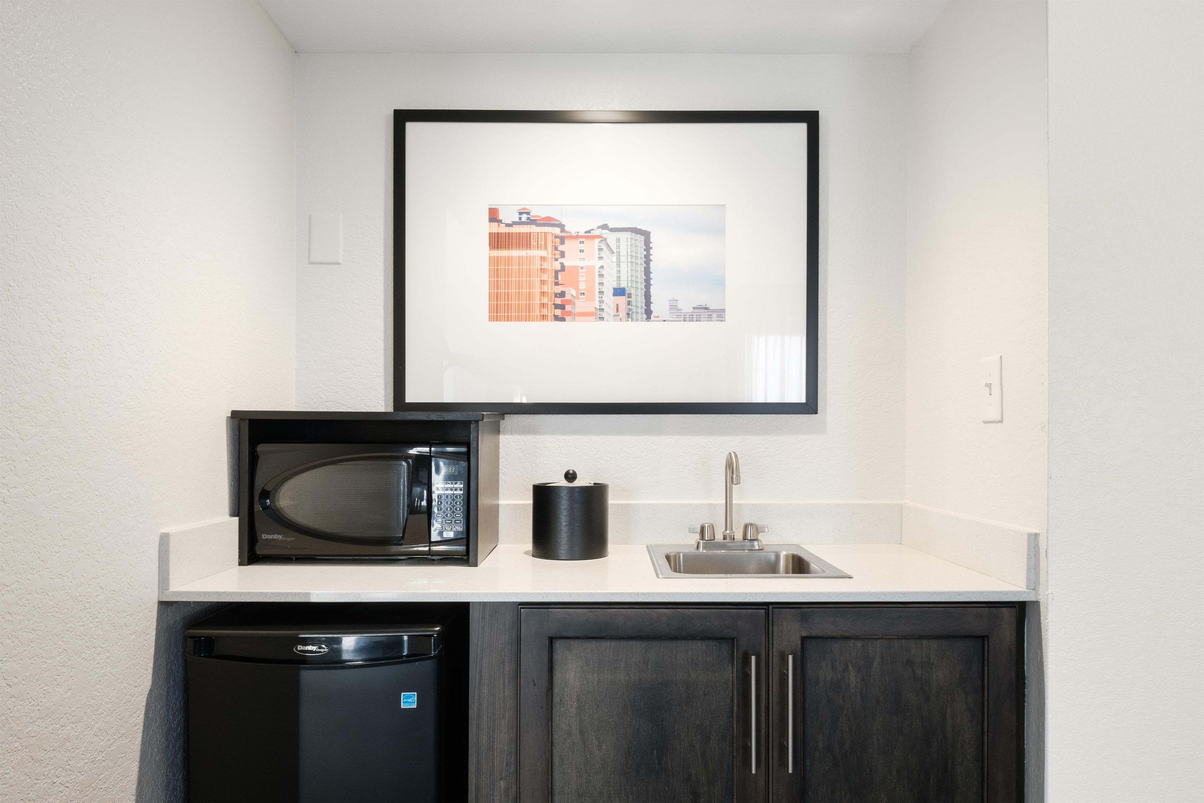 A compact kitchenette with a microwave, sink, and cabinet.