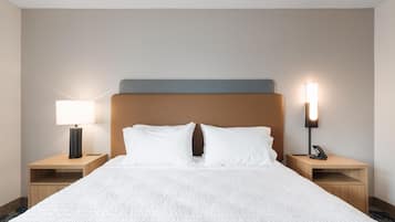 A hotel room with a large bed, two bedside tables, a nightstand, a lamp, and a phone on the nightstand.