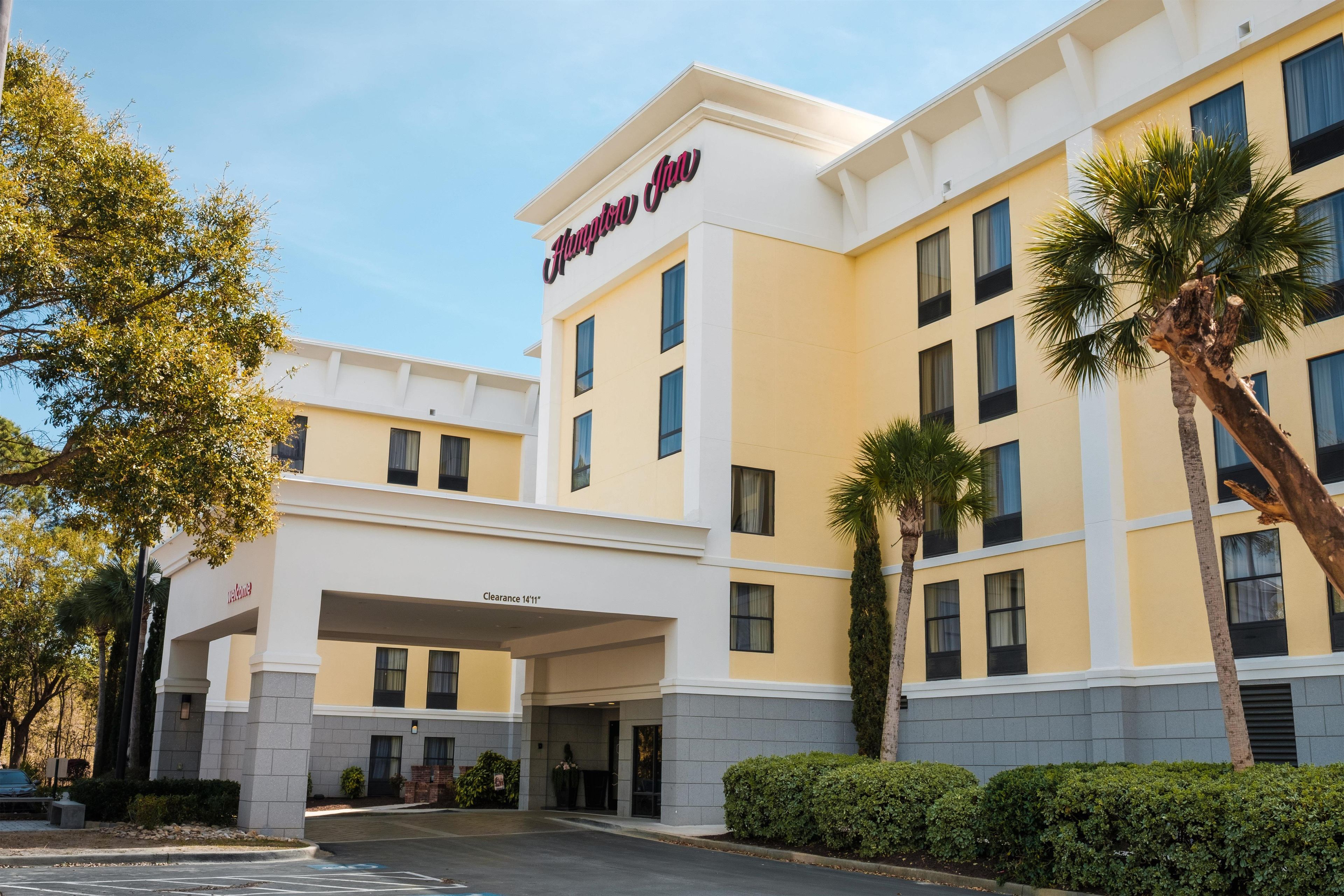 A hotel with a clear entrance, a sign reading 'Hampton Inn,' and a parking area.