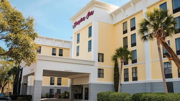 A hotel with a clear entrance, a sign reading 'Hampton Inn,' and a parking area.