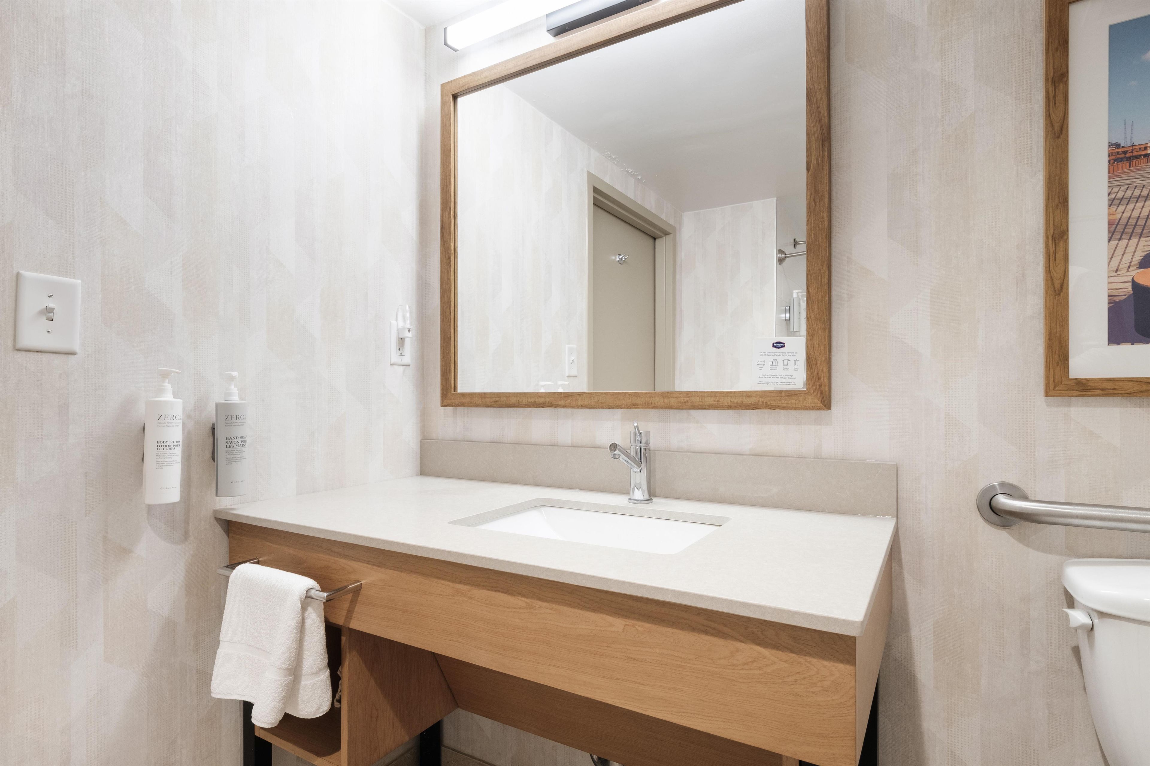 Un baño con tocador de madera, un lavamanos blanco, un espejo y una barandilla.