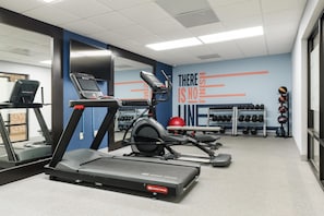 Un gimnasio con cintas de correr, una bicicleta estática y una pared con mensajes motivacionales.