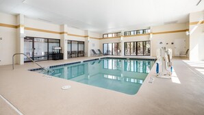 Una piscina interior con paredes de vidrio transparente, sillas de descanso y un puesto de socorristas.