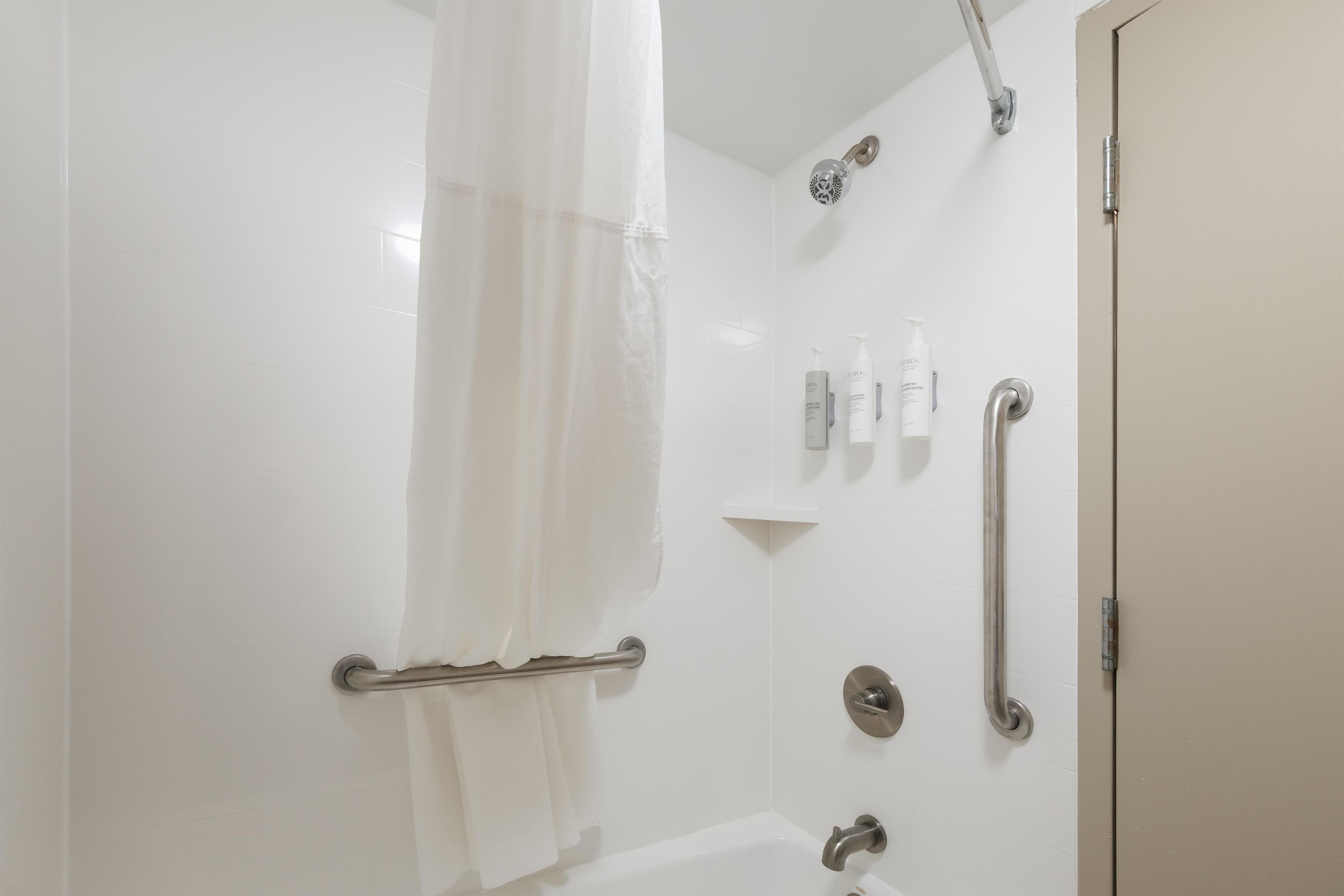 Een moderne badkamer met een douche, handgrepen en een handdoekhouder.