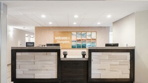 Una mesa de recepción con un cartel que dice 'Welcome to Hampton', una placa de 'Hilton Honors' y vista al océano a través de una ventana.
