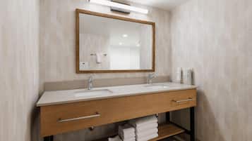 Une salle de bain moderne avec un meuble-lavabo en bois, deux vasques, un grand miroir et une étagère à serviettes.