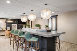 Una cocina moderna con una isla central, taburetes de bar, iluminación colgante y vistas al área de comedor.