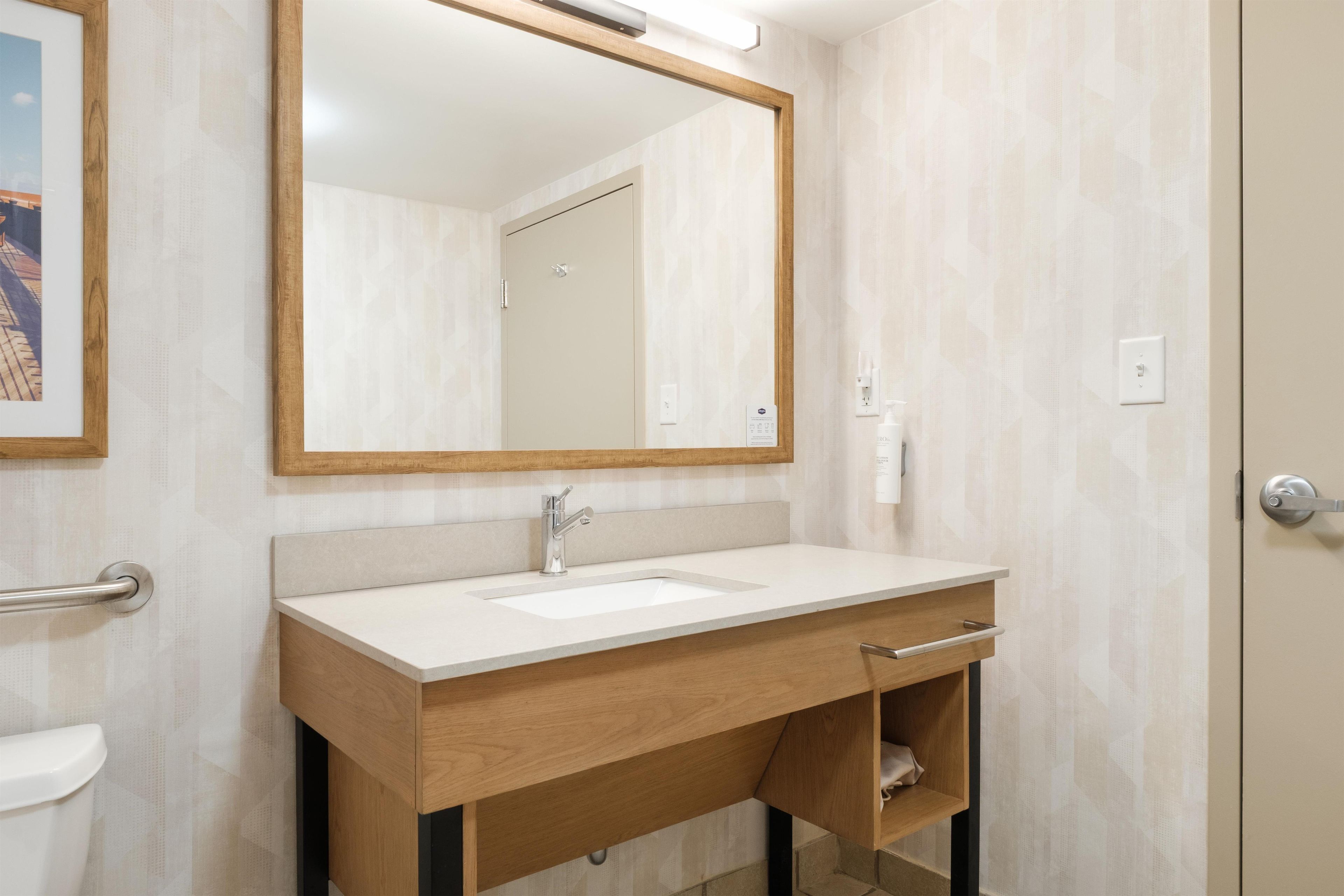 Ein Badezimmer mit einem Holzlagerflächen, einem Waschbecken, einem Spiegel und einer Toilette.