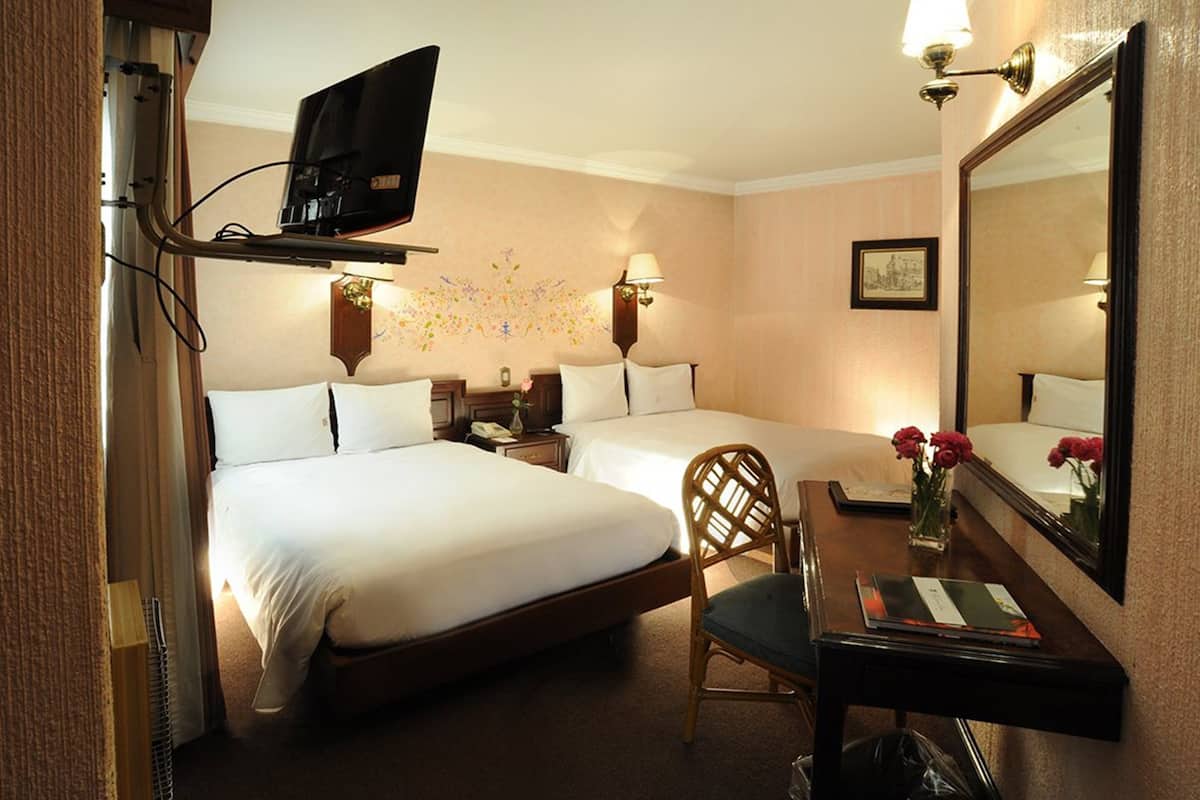 Une chambre d’hôtel avec deux lits, un bureau, une chaise, une télévision et un miroir.