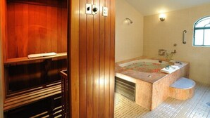 Una sauna de madera con un banco, una bañera independiente grande y un ventanal con vistas.
