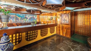 Una zona de recepción con mostrador de madera, un jarrón decorativo grande y techo con vigas a la vista.