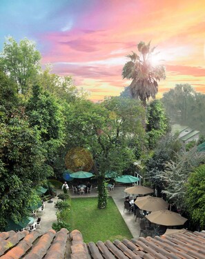 Un exuberante jardín con mobiliario exterior y vistas al atardecer.