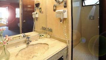 Casa de banho com lavatório, espelho, secador de cabelo e chuveiro.