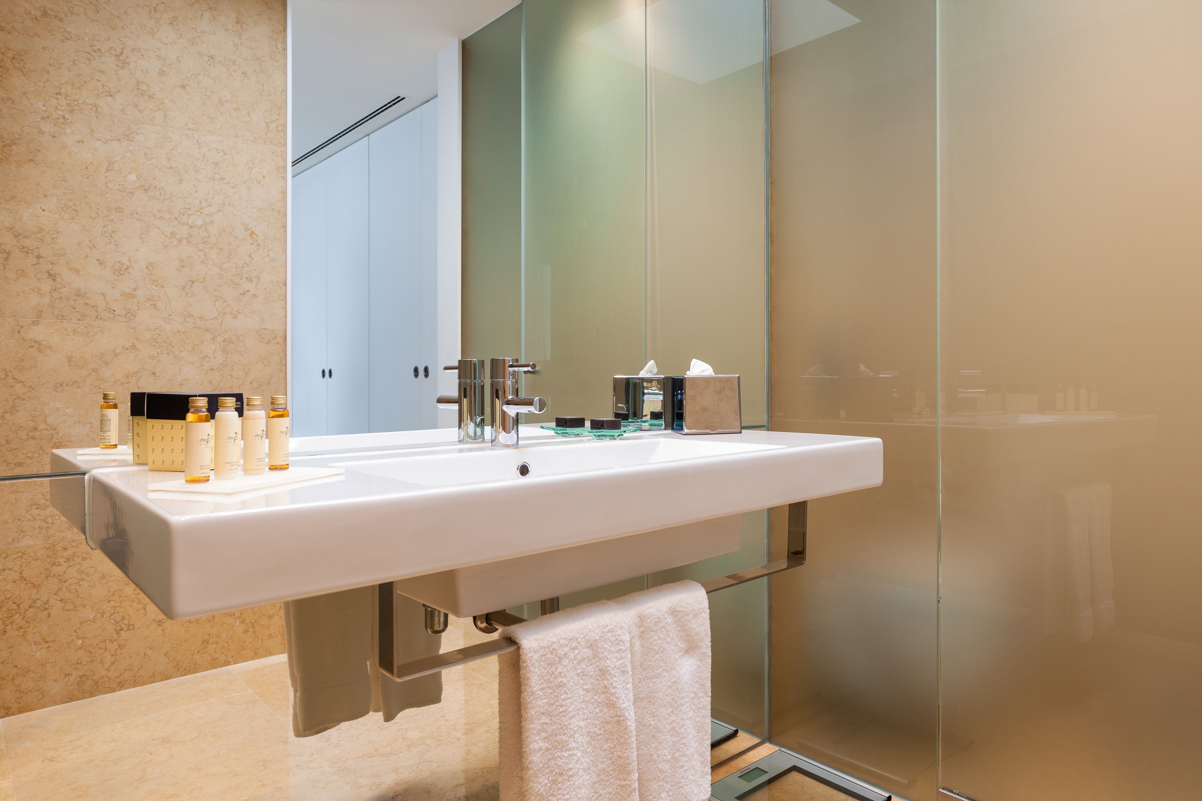 A modern bathroom with a large white sink, glass shower enclosure, and a mirror above the sink.