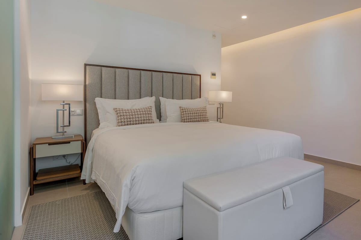A modern bedroom with a large bed, bedside tables, and a bench.