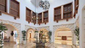 A spacious lobby with a reception area, arched doorways, and a central decorative table.