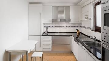 A compact kitchen with white cabinets, a black countertop, and a tiled backsplash.