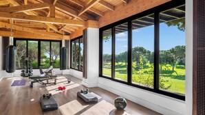 A spacious gym with wooden beams, large windows, and a view of a golf course.