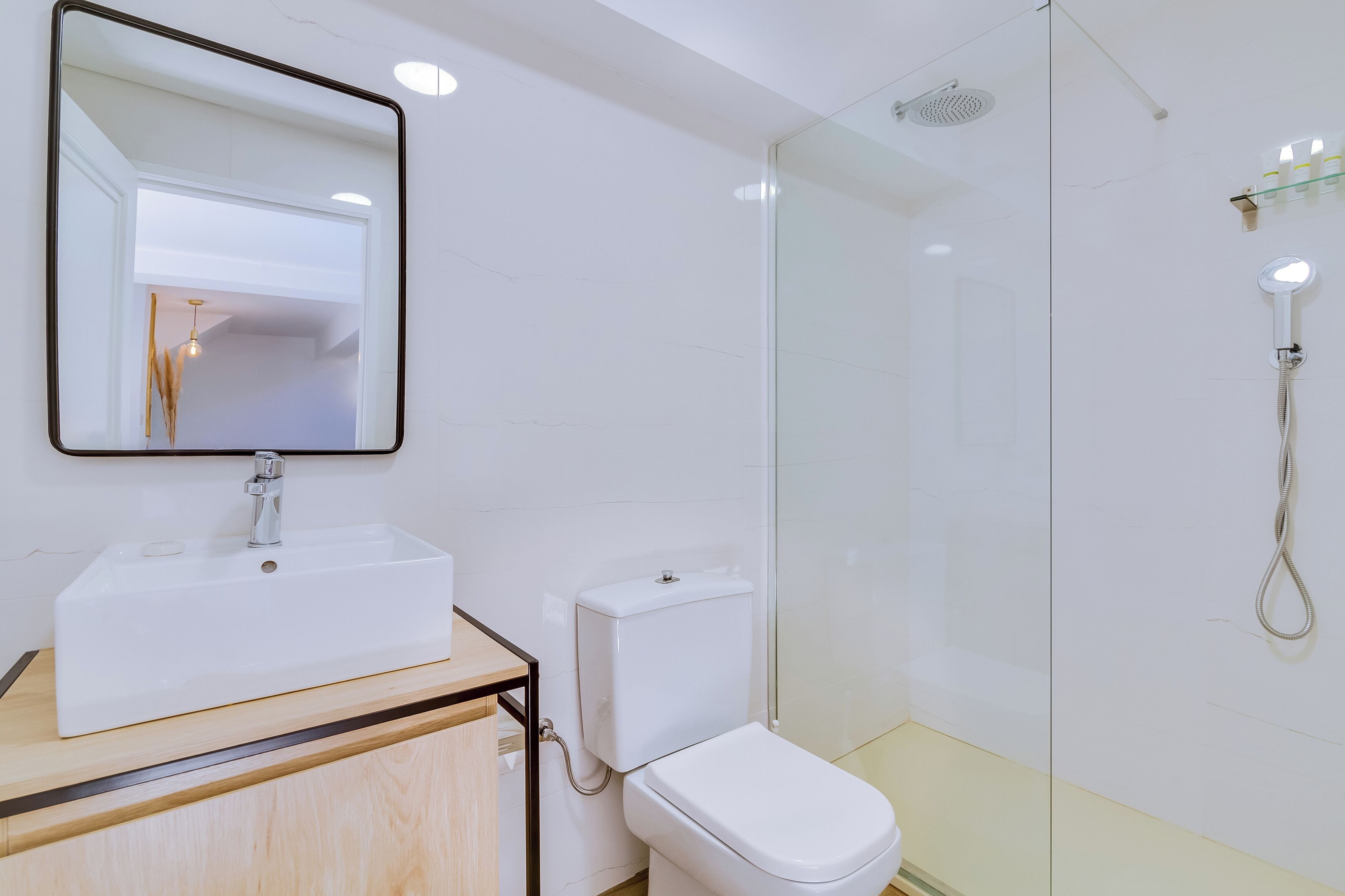 A modern bathroom with a white sink, toilet, and glass shower enclosure.