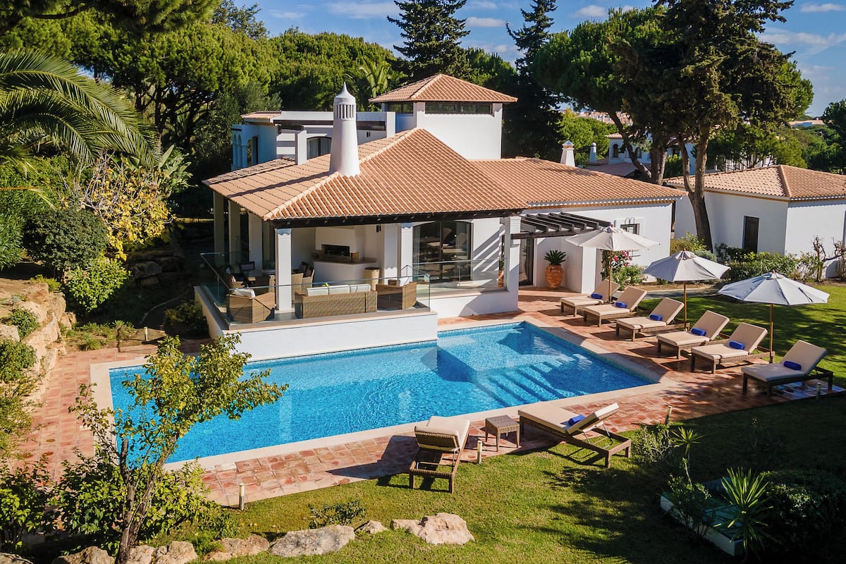 A modern house with a swimming pool, outdoor seating, and a garden.