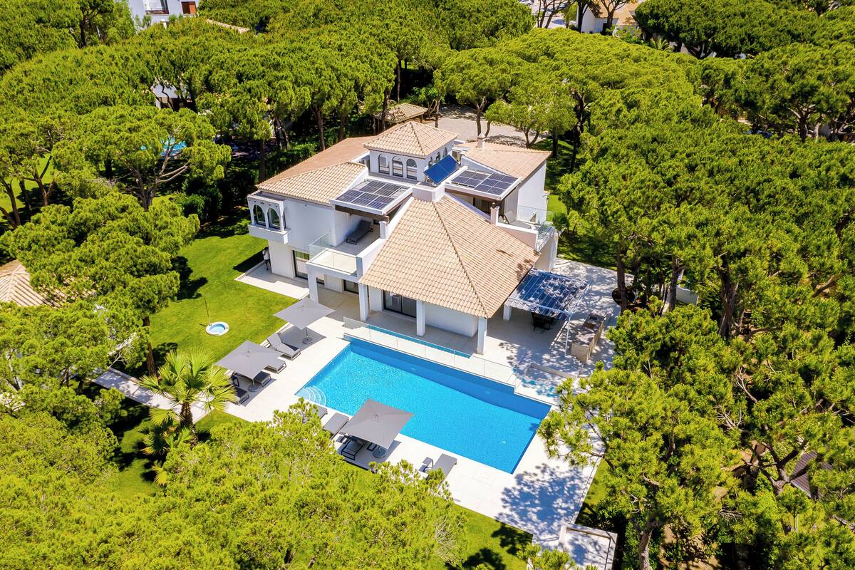 A large house with a swimming pool surrounded by trees.