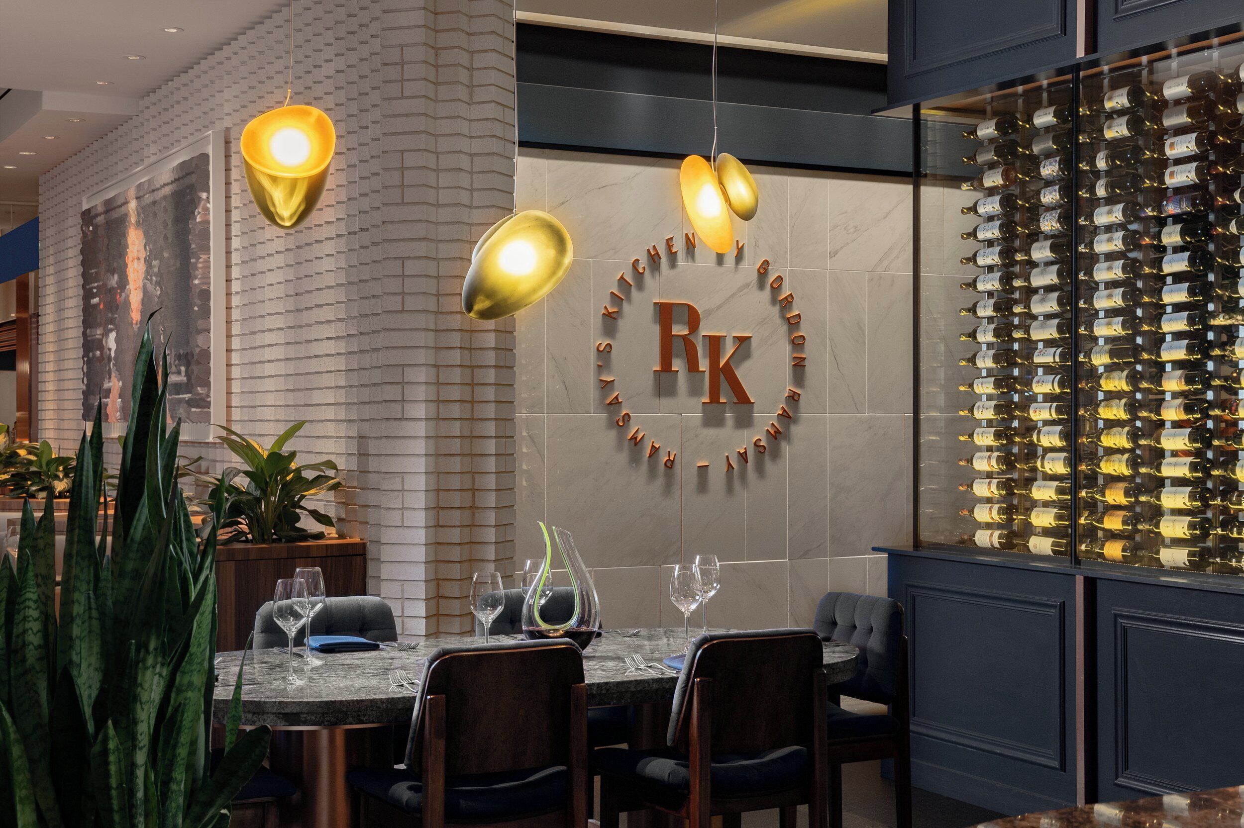 Un restaurant doté d’un bar à vin, d’une table dressée pour le dîner et de luminaires suspendus.