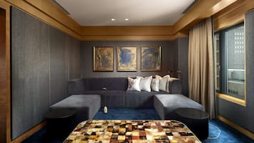A modern hotel room with a grey sofa, a patterned coffee table, and three framed artworks on the wall.