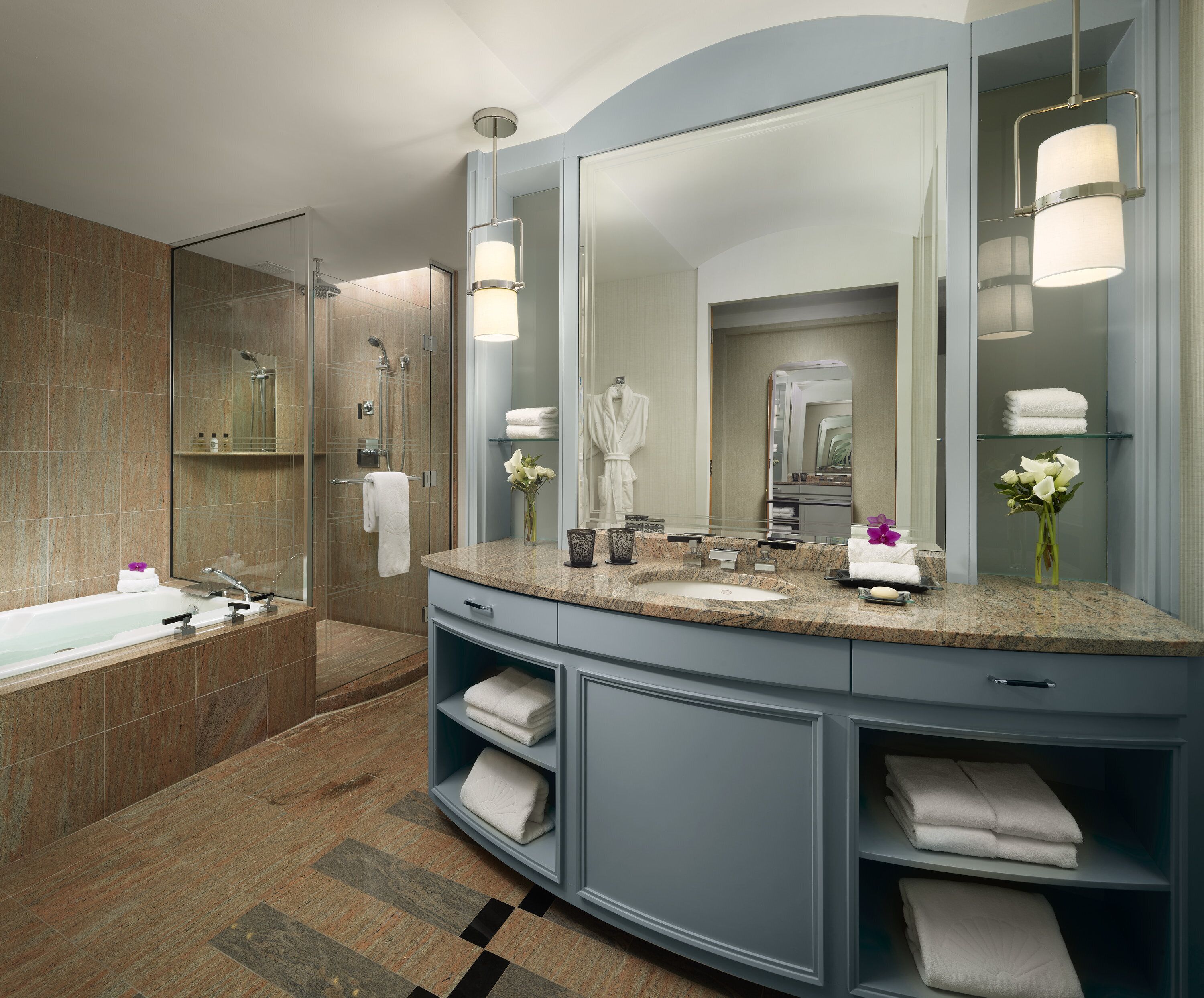 A modern bathroom with a large mirror, a bathtub, and a vanity with shelves for towels.