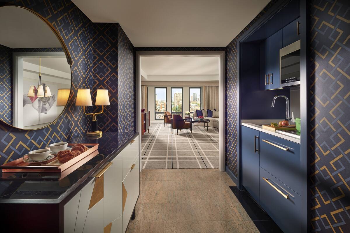 A modern hotel room with a large mirror, a breakfast tray, and a view of the city through large windows.