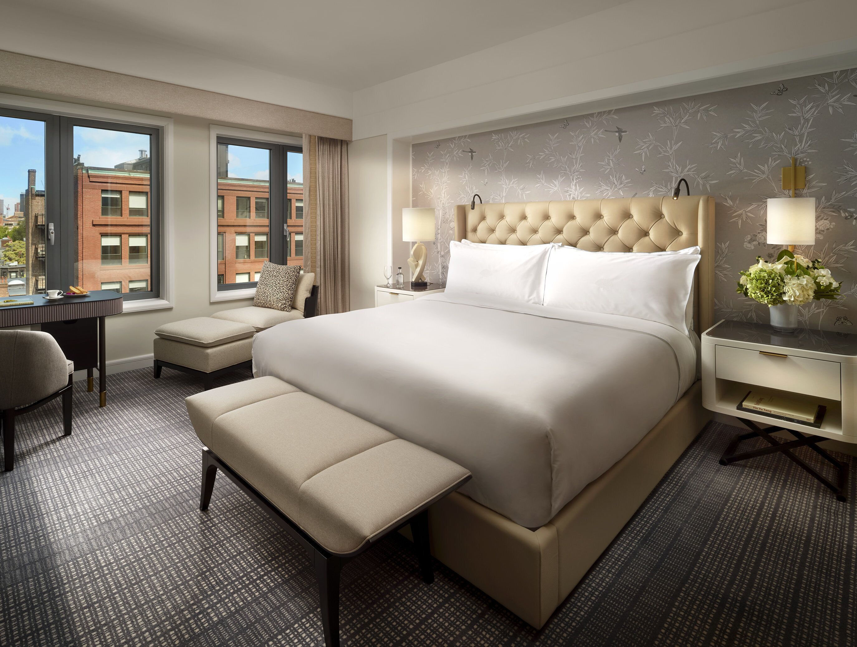Quarto de hotel com cama grande, escrivaninha, cadeira e vista para a cidade.