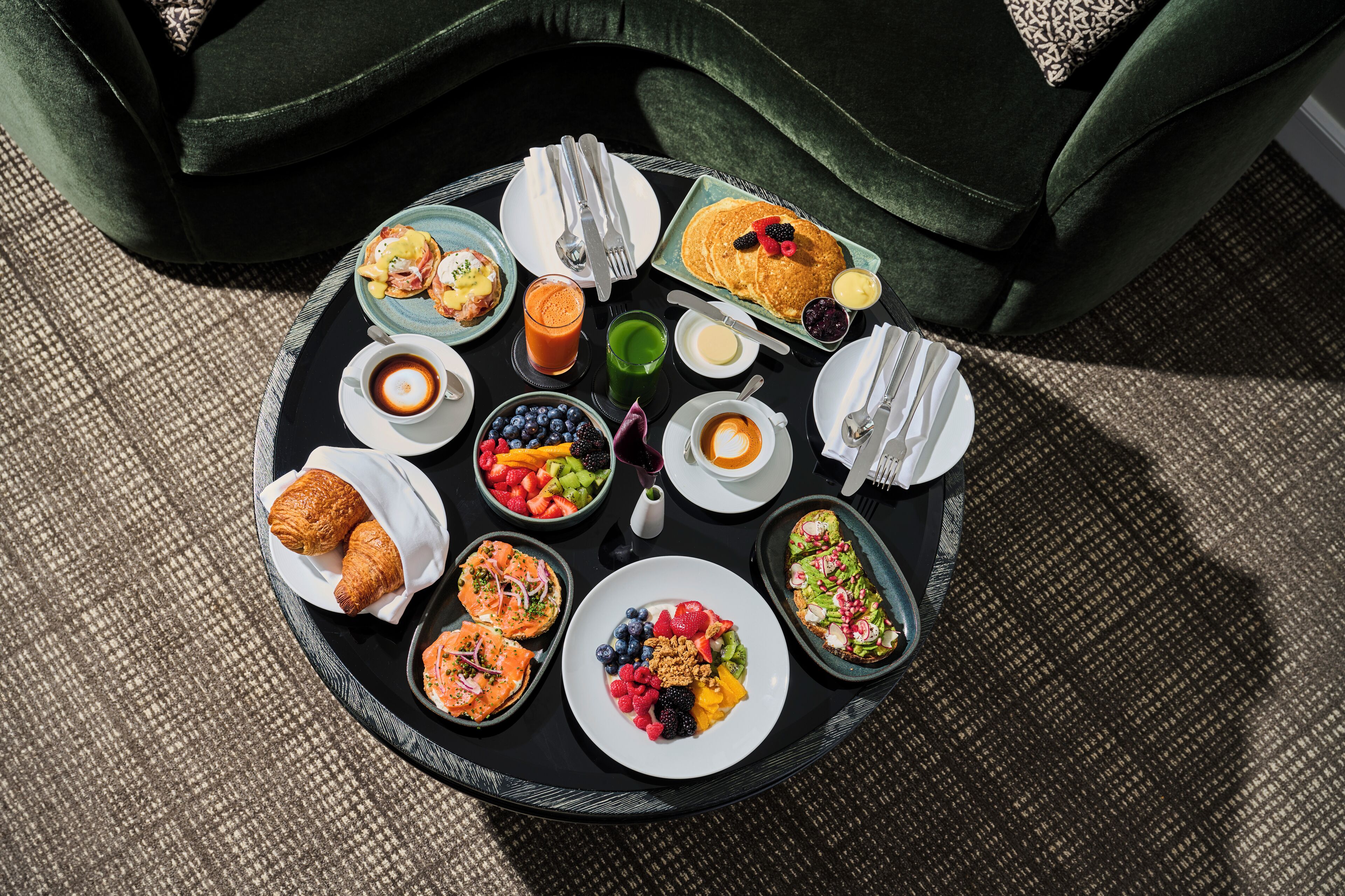 A round dining table with various breakfast items including pastries, fruits, and beverages.