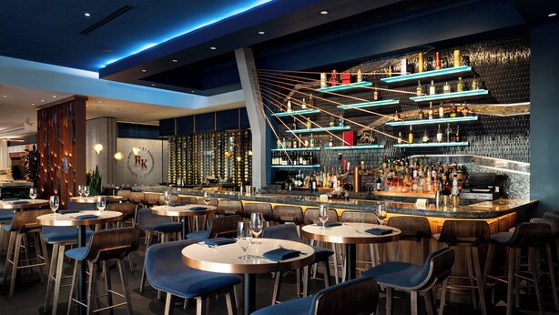 A modern bar area with multiple seating options, a well-stocked bar counter, and a distinctive ceiling design. - Mandarin Oriental, Boston (Boston)