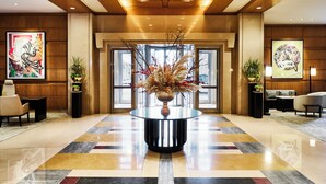 A lobby with a central round table, potted plants, and artwork on the walls. - Mandarin Oriental, Boston (Boston)