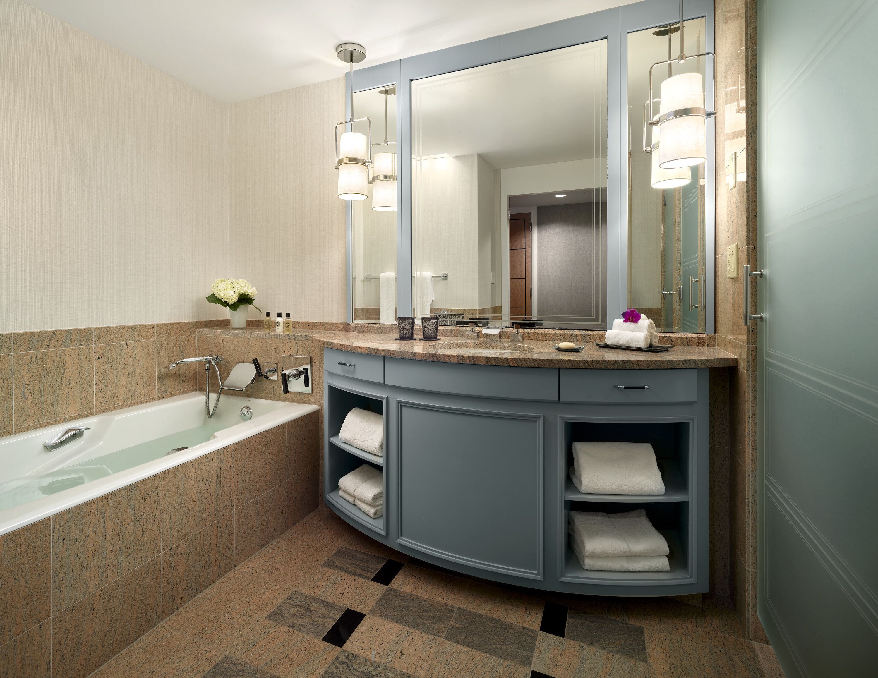 A modern bathroom with a freestanding bathtub, a large mirror, and a vanity with a sink and towel storage.