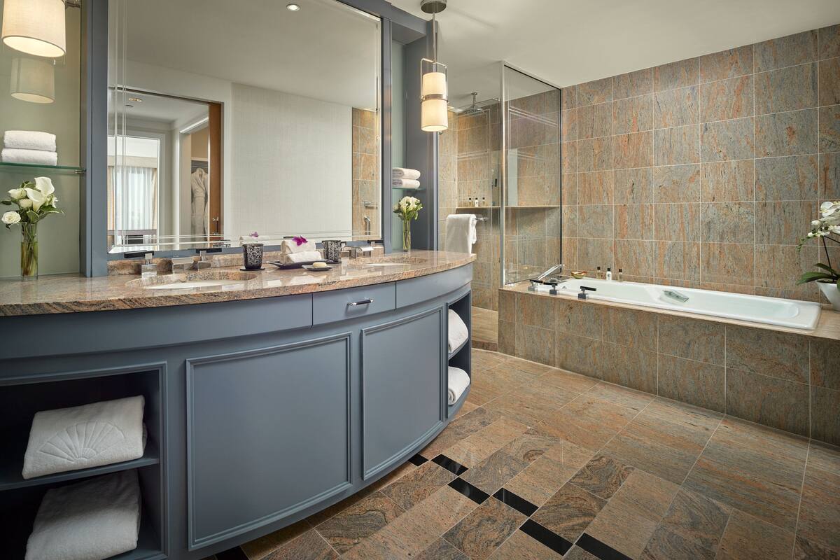 A modern bathroom with a large vanity, a bathtub, and a shower area.