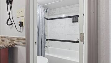 Een badkamer met een wit bad, een toilet en een douchehoek.